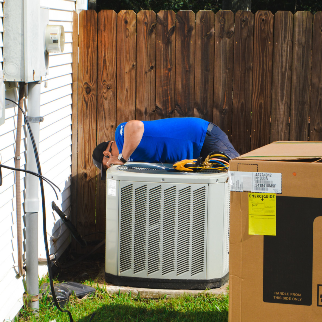 A man is repairing an air conditioner, focused on the unit with tools in hand, ensuring optimal performance.